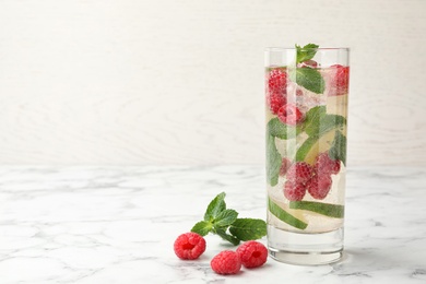 Glass of refreshing drink with raspberry, lime and mint on marble table against white background, space for text