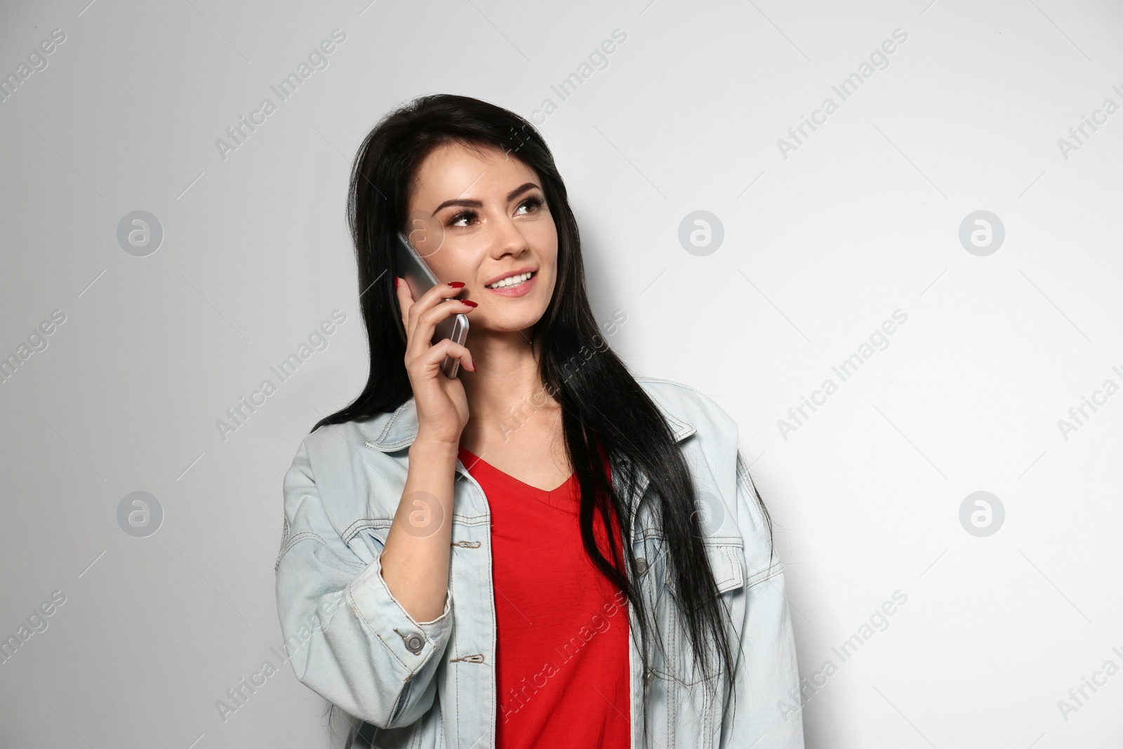 Photo of Portrait of stylish woman talking on phone against light background