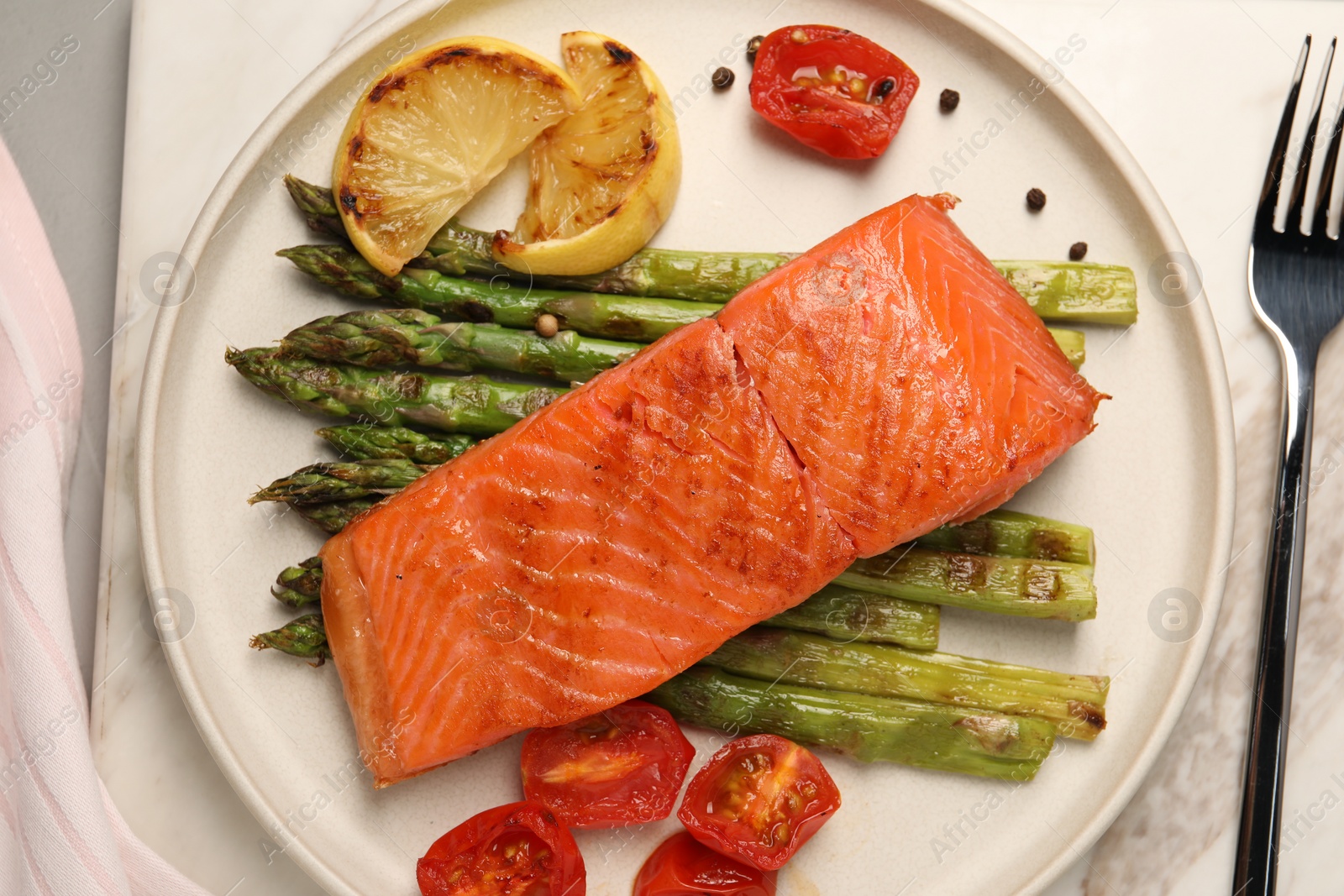 Photo of Tasty grilled salmon with asparagus, tomatoes, spices and lemon served on light grey table, top view