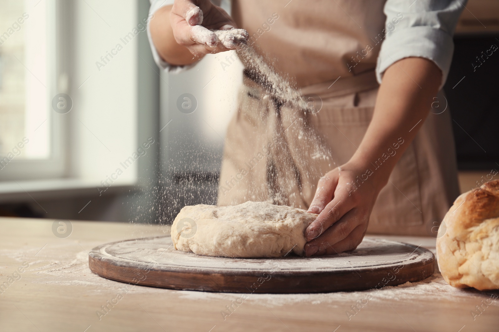 Photo of Female baker preparing bread dough at table, closeup