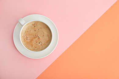 Cup of coffee on color background, top view. Space for text