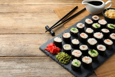 Photo of Tasty sushi rolls served on wooden table. Space for text