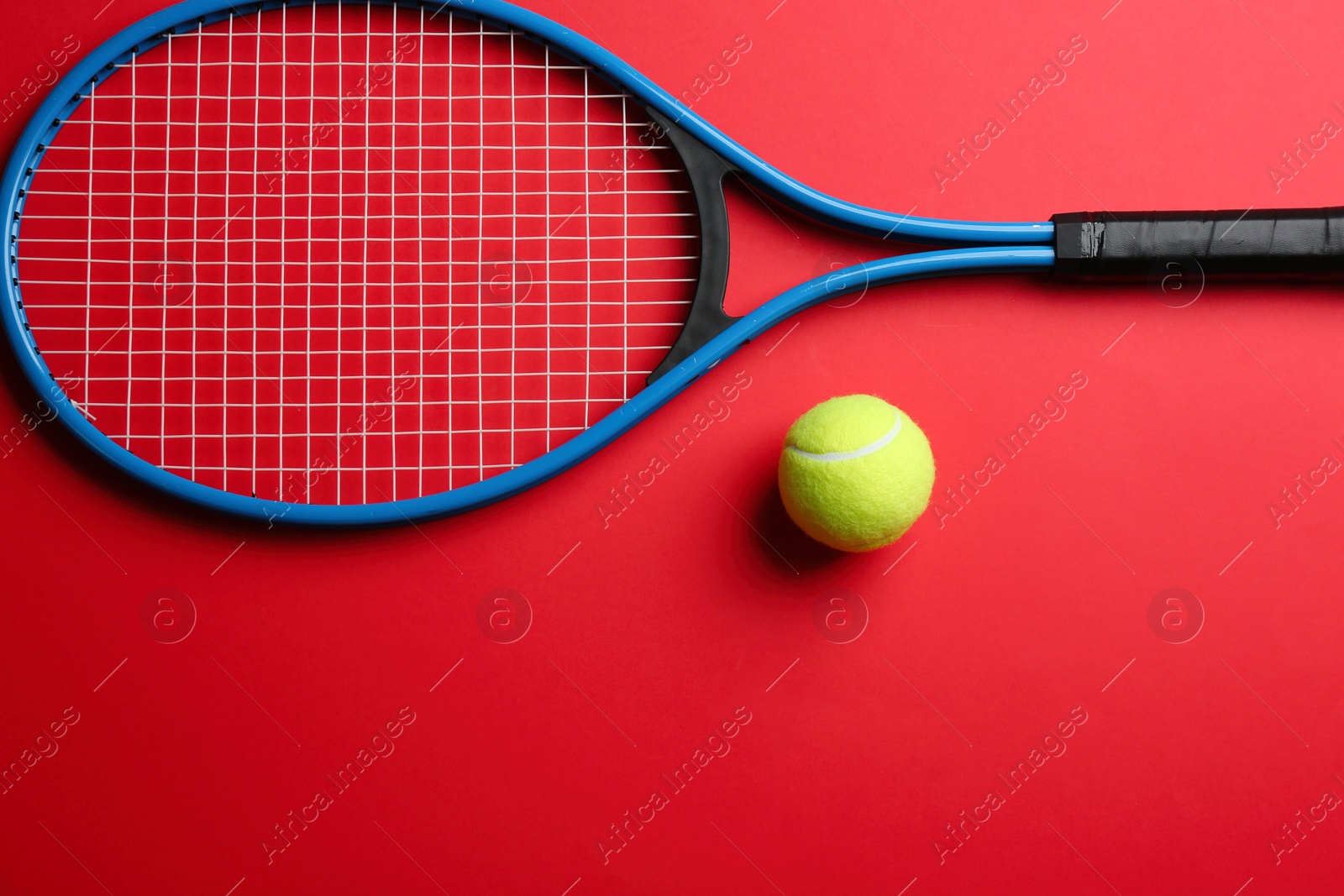 Photo of Tennis racket and ball on red background, flat lay. Space for text