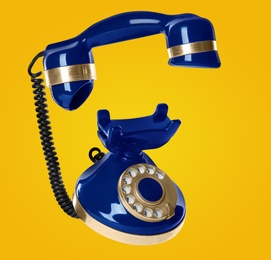 Image of Vintage blue corded telephone flying in air on yellow background