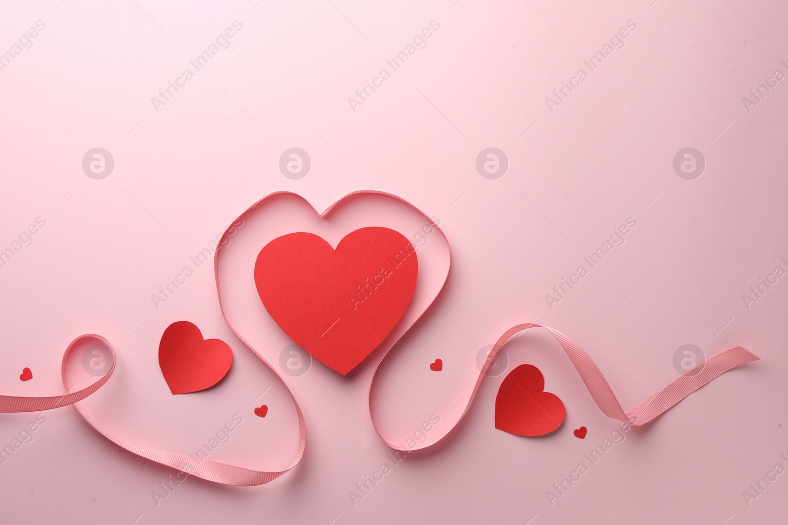 Photo of Paper hearts and ribbon on pink background, flat lay. Space for text