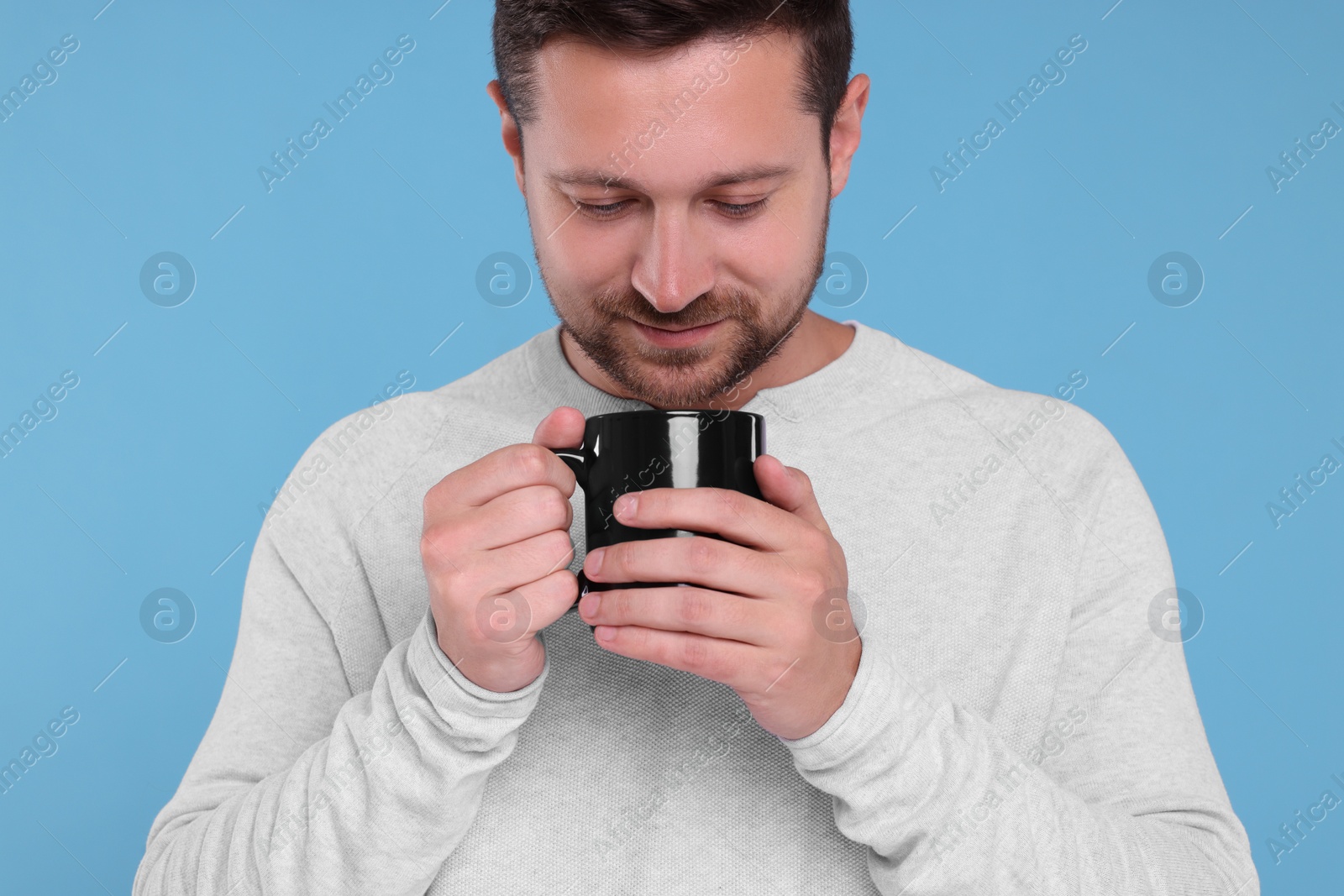 Photo of Man holding black mug on light blue background