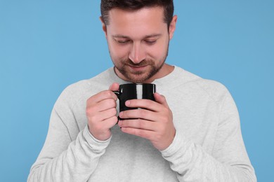 Photo of Man holding black mug on light blue background