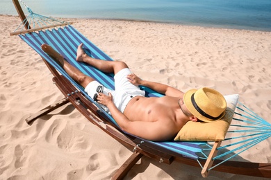 Young man relaxing in hammock on beach