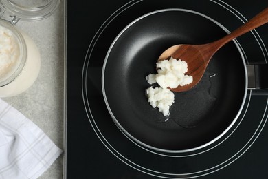 Frying pan with coconut oil and wooden spatula on induction stove, top view. Healthy cooking