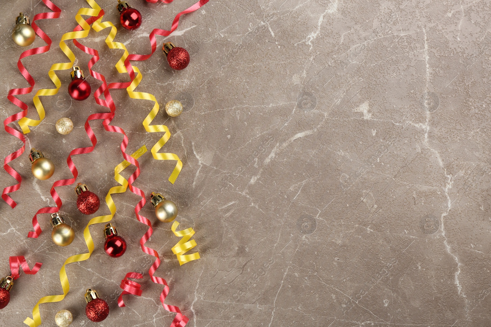 Photo of Colorful serpentine streamers and Christmas balls on grey background, flat lay. Space for text