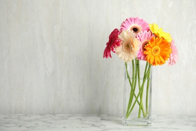 Photo of Bouquet of beautiful bright gerbera flowers in vase on marble table against light background. Space for text