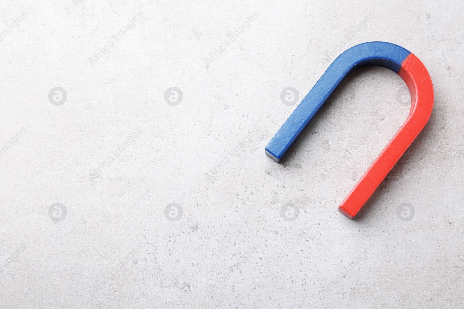 Photo of Red and blue horseshoe magnet on grey background, top view with space for text