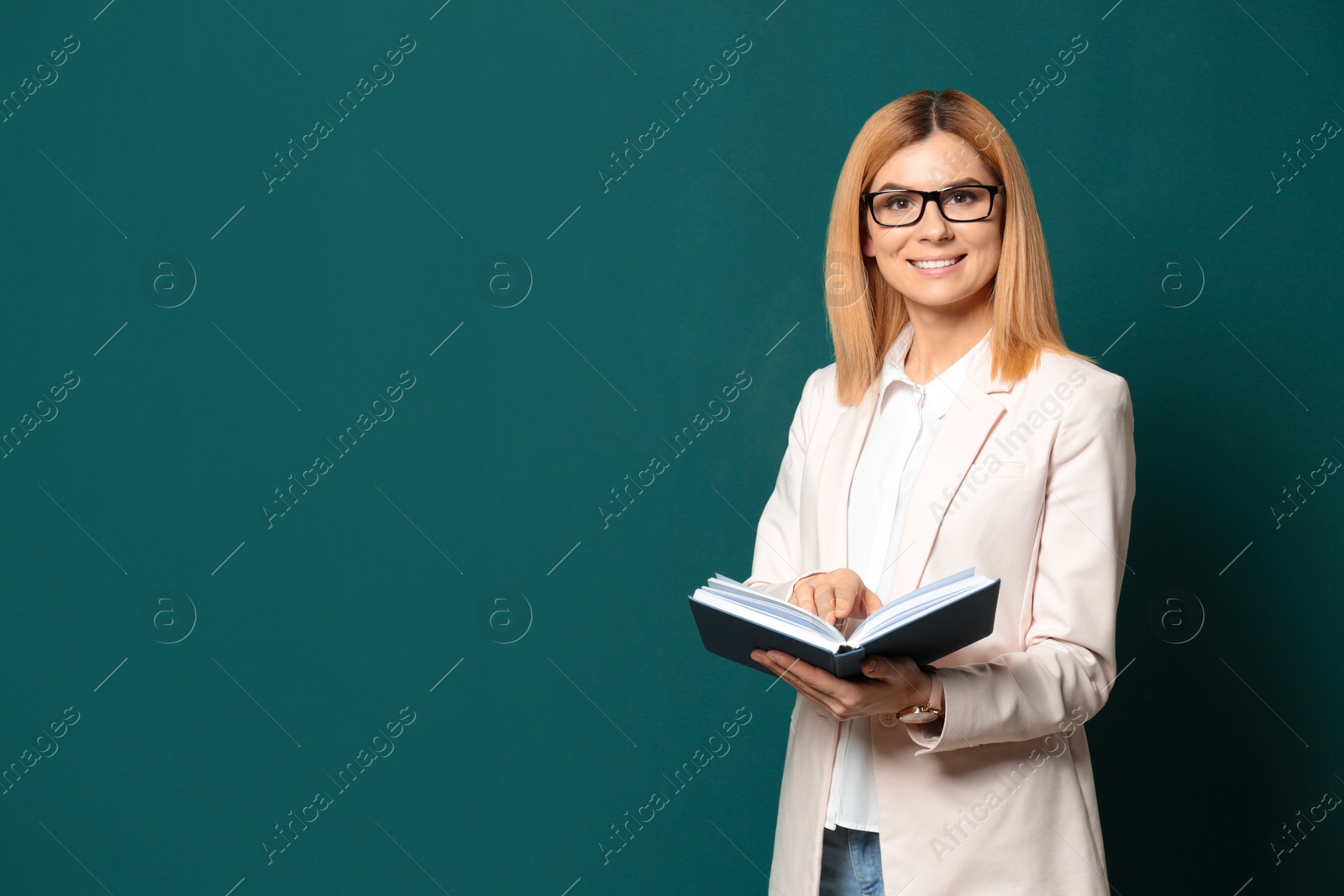 Photo of Portrait of beautiful teacher with book near chalkboard, space for text