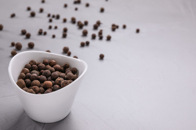 Black peppercorns in bowl on grey table. Space for text