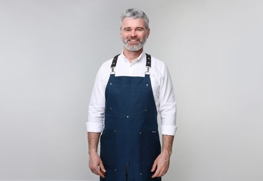 Photo of Happy man wearing kitchen apron on grey background. Mockup for design