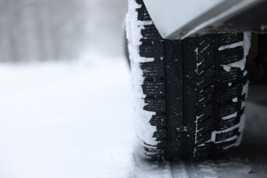 Photo of Car with winter tires on snowy road outdoors, closeup. Space for text