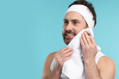 Photo of Washing face. Man with headband and towel on light blue background, space for text