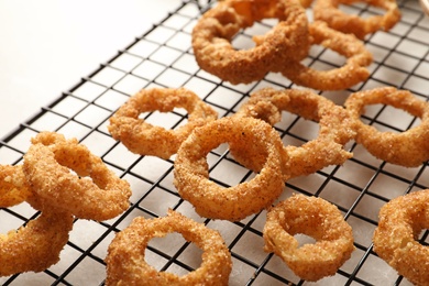 Cooling rack with homemade crunchy fried onion rings on table, closeup