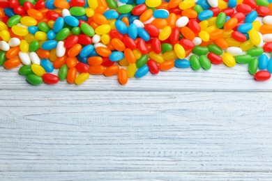 Photo of Colorful jelly beans on white wooden background, flat lay. Space for text