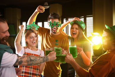 Photo of Group of friends toasting with green beer in pub. St. Patrick's Day celebration