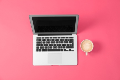 Photo of Modern laptop and cup of coffee on pink background, flat lay