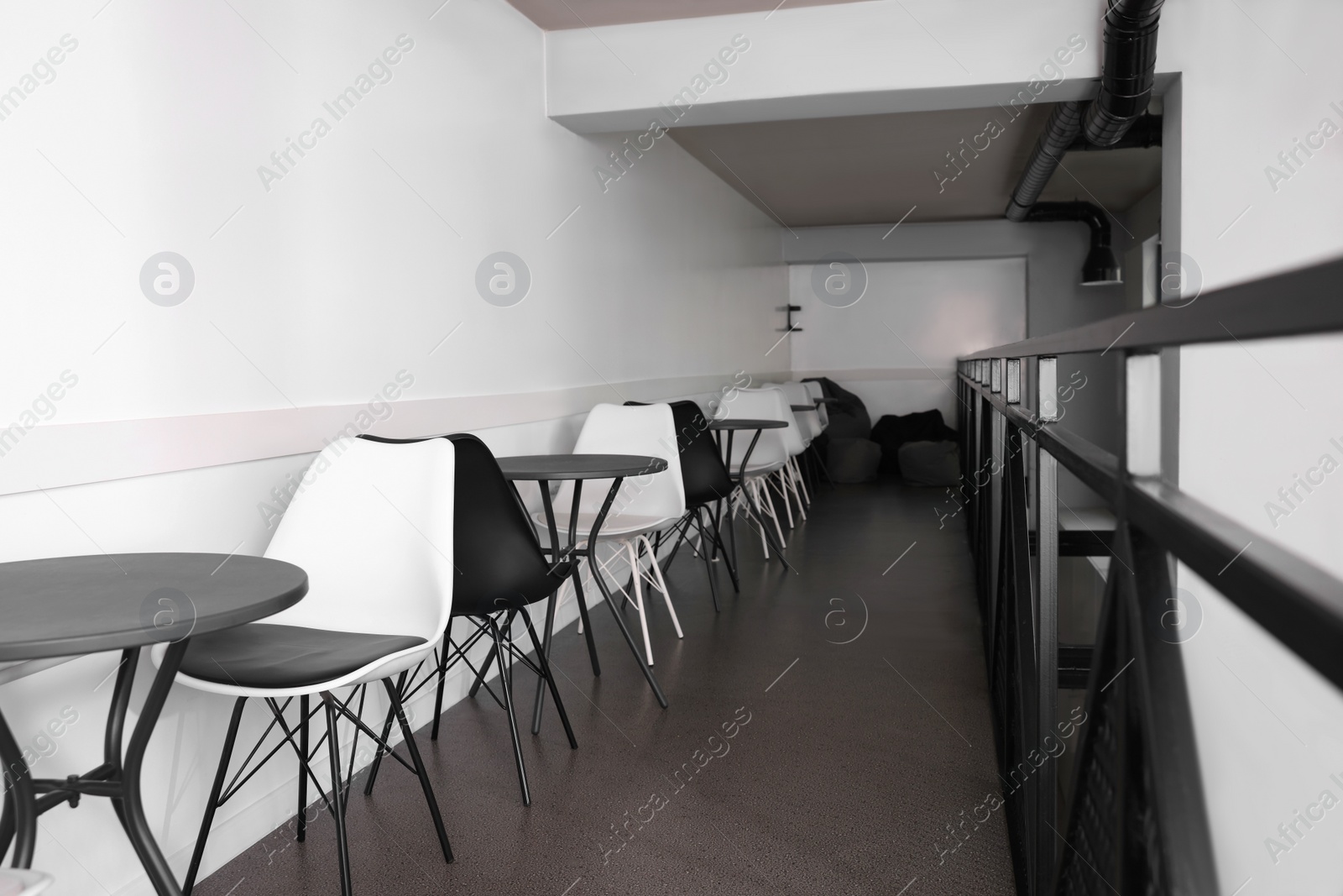 Photo of Hostel dining room interior with tables and chairs along white wall