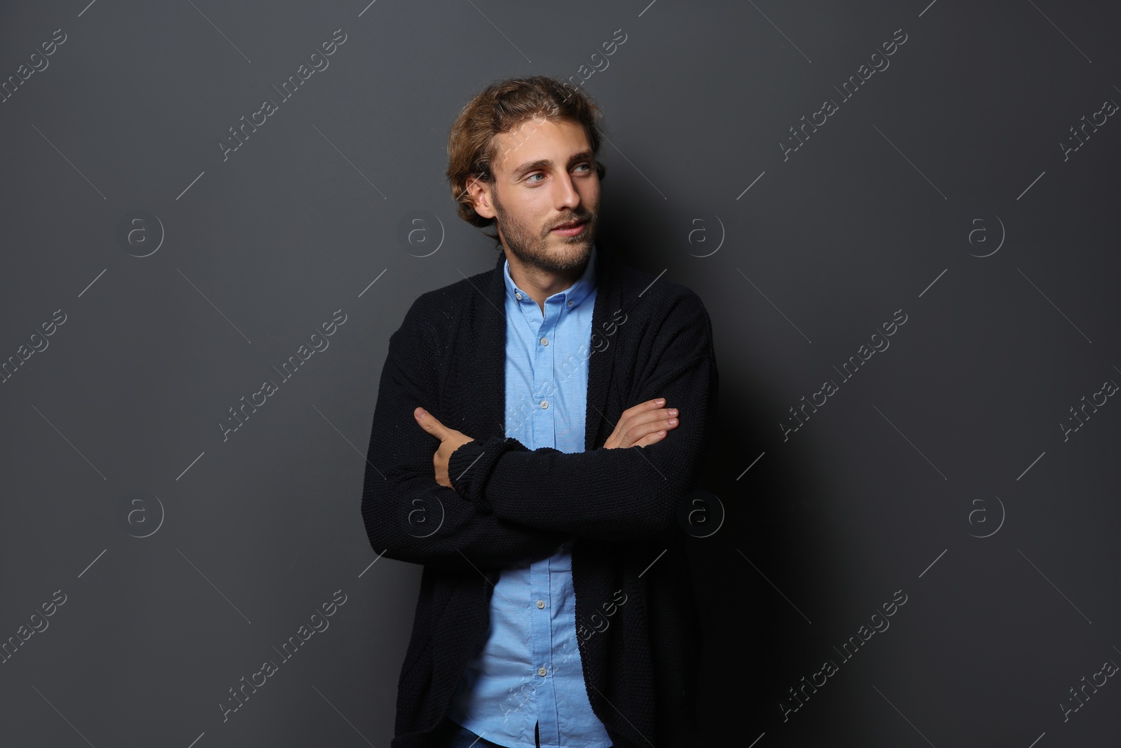 Photo of Handsome young man in shirt and warm sweater on dark background