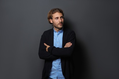 Handsome young man in shirt and warm sweater on dark background