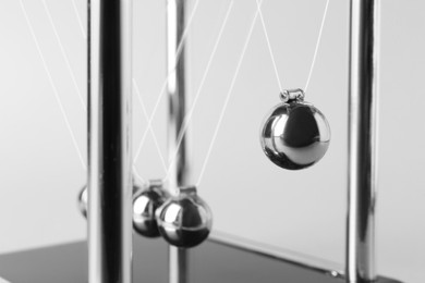 Photo of Newton's cradle on light background, closeup. Physics law of energy conservation