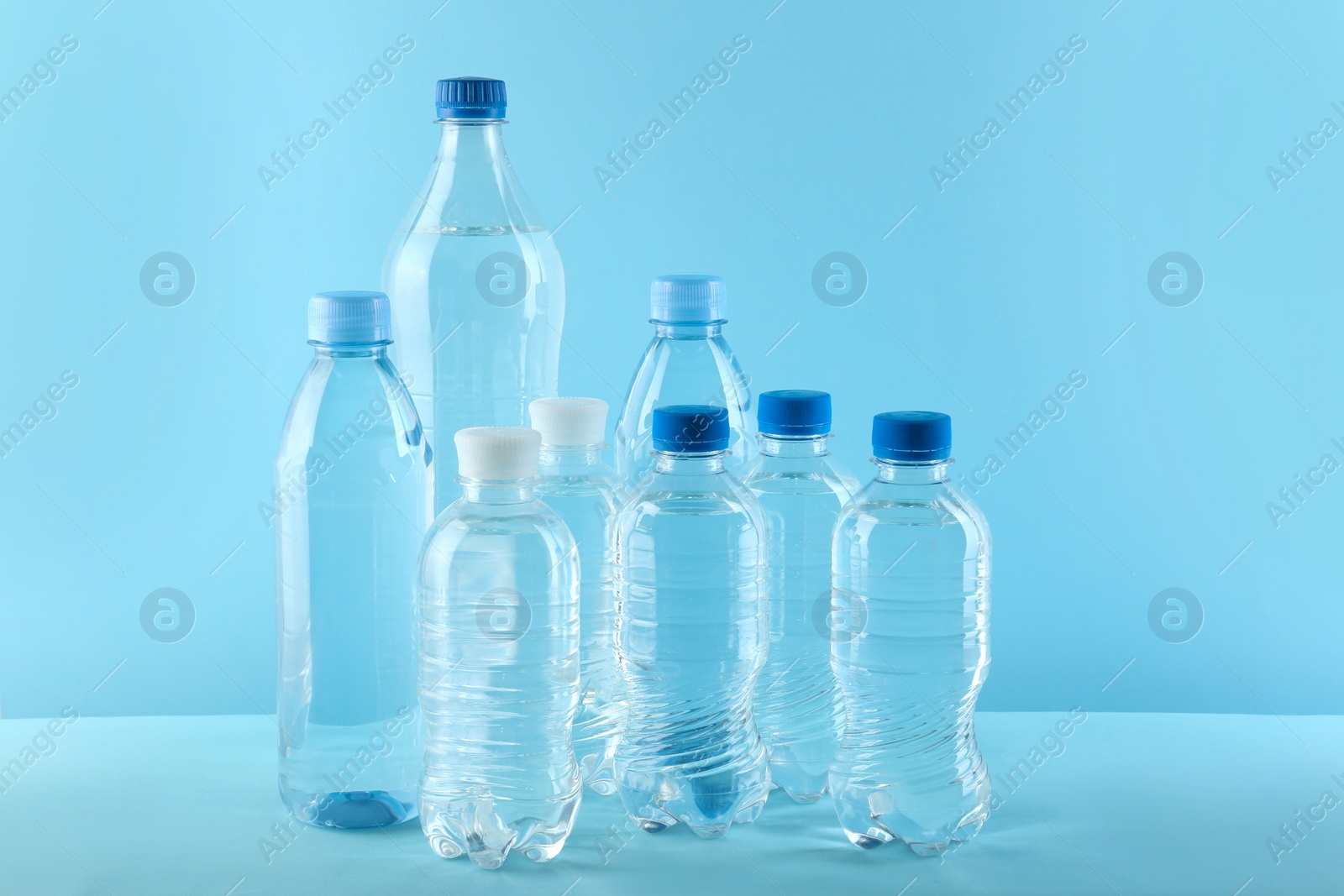 Photo of Set of different plastic bottles with water on blue background