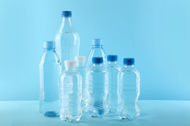 Set of different plastic bottles with water on blue background