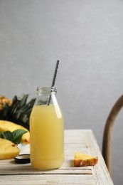 Photo of Delicious pineapple juice and fresh fruit on table indoors