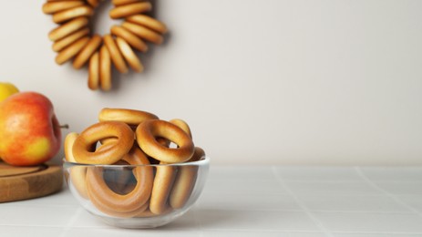 Photo of Bowl with delicious ring shaped Sushki (dry bagels) on white table. Space for text