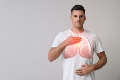 Image of Handsome man holding hands near chest with illustration of lungs on grey background. Space for text