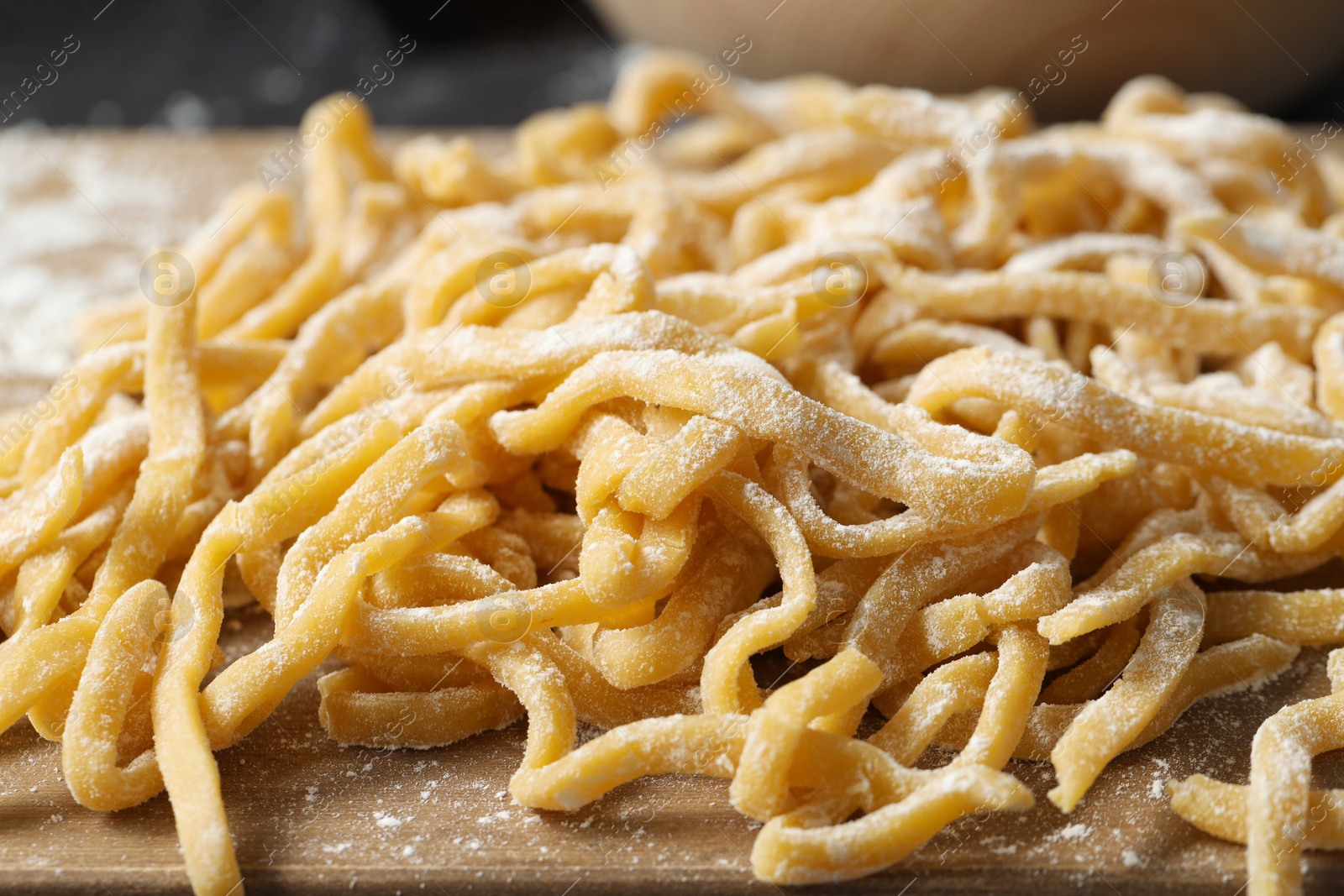 Photo of Raw homemade pasta and flour on board, closeup