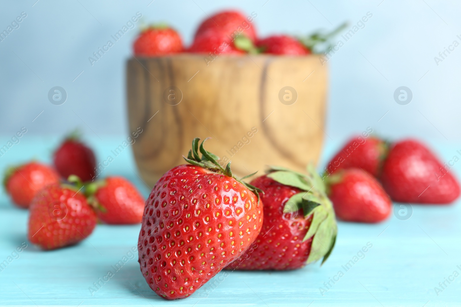 Photo of Delicious ripe strawberries on light blue wooden table, closeup