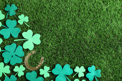 Photo of Flat lay composition with clover leaves on green grass, space for text. St. Patrick's Day celebration