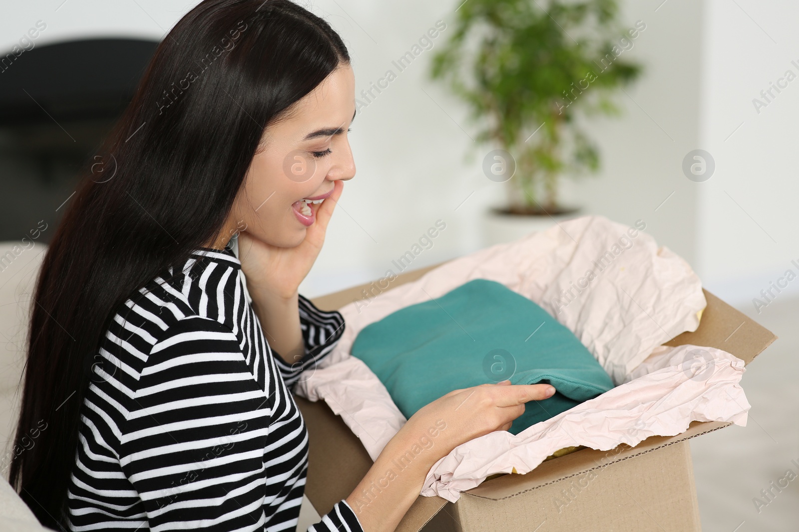 Photo of Happy young woman with parcel at home. Internet shopping