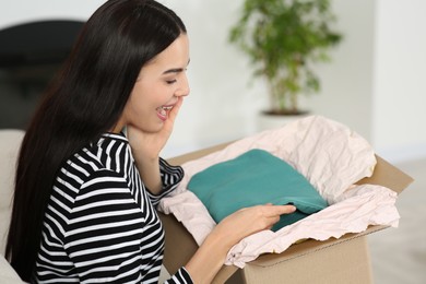 Photo of Happy young woman with parcel at home. Internet shopping