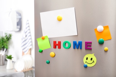 Photo of Word HOME of magnetic letters and paper sheets on refrigerator door indoors. Space for text