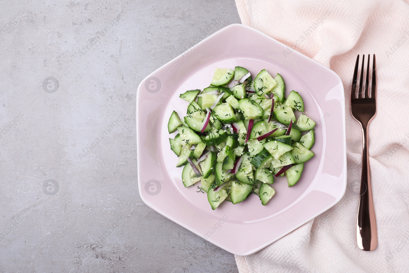 Photo of Plate of vegetarian salad with cucumber and onion served on table, flat lay. space for text