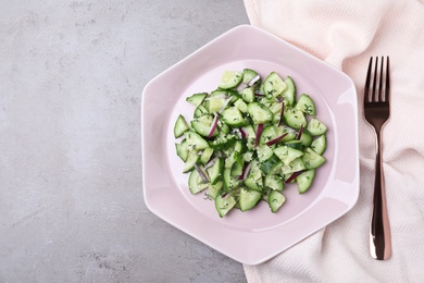 Plate of vegetarian salad with cucumber and onion served on table, flat lay. space for text