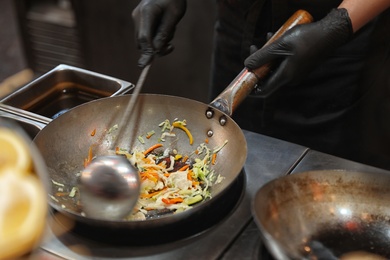 Photo of Man frying delicious vegetables in kitchen, closeup