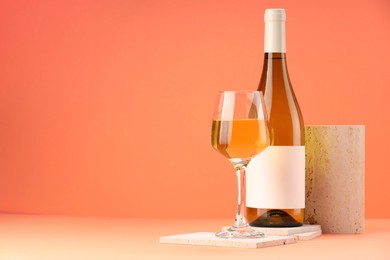 Stylish presentation of delicious wine in bottle and glass on orange background. Space for text