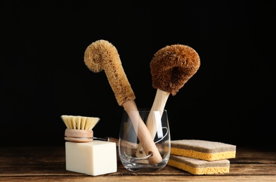Photo of Cleaning supplies for dish washing on wooden table against black background