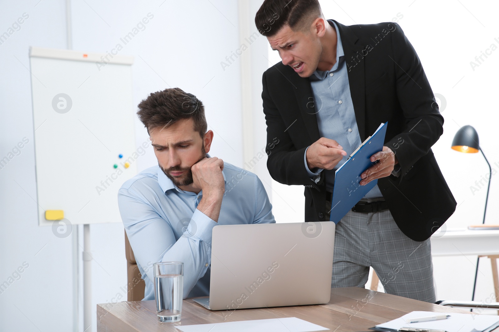 Photo of Boss screaming at employee in office. Toxic work environment