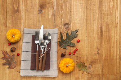 Cutlery, napkins and autumn decoration on wooden background, flat lay with space for text. Table setting