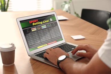 Image of Man betting on sports using laptop at table, closeup. Bookmaker website on screen