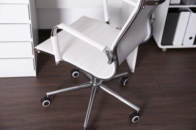 Photo of Comfortable rolling chair near table in modern office