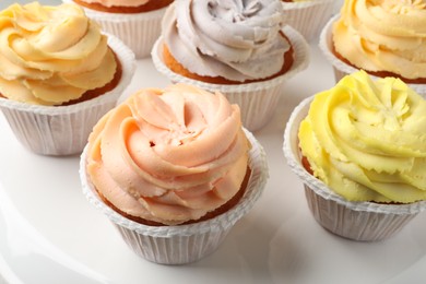 Tasty cupcakes with cream on white stand, closeup